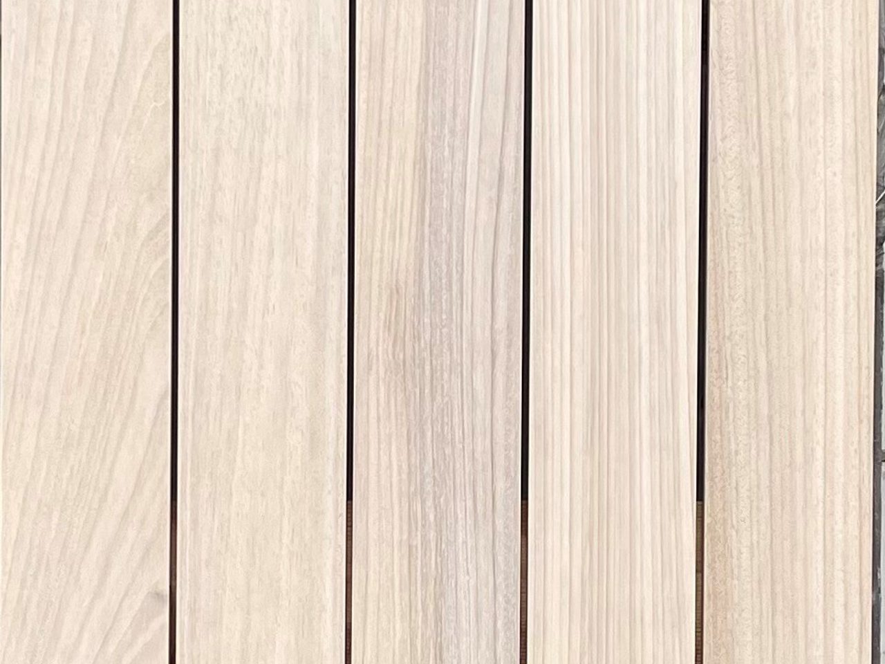 Light wood decking boards arranged vertically, showing grain patterns and small screws along the edges.