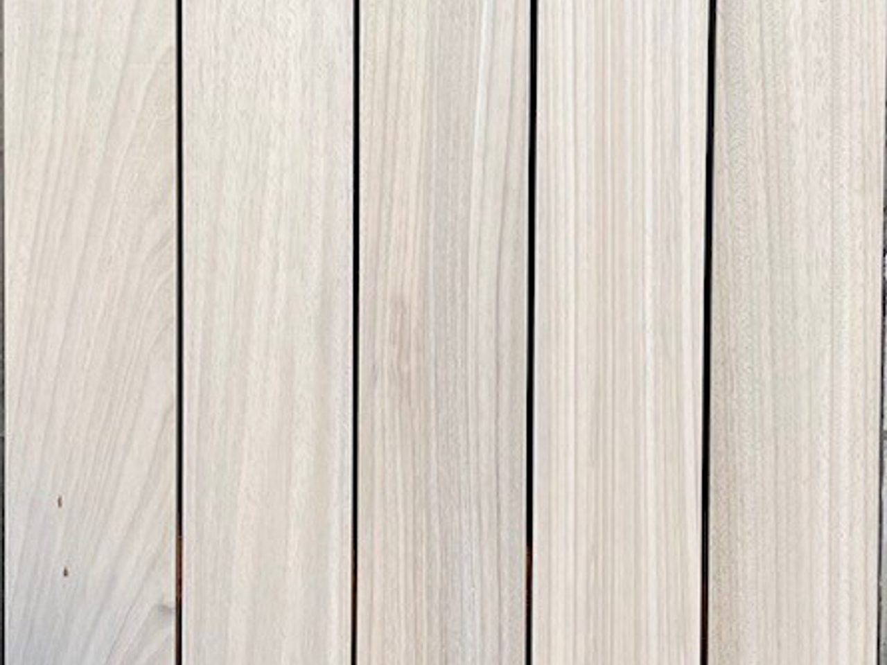 Close-up of light-colored wood planks arranged vertically with visible grain and narrow gaps between them.