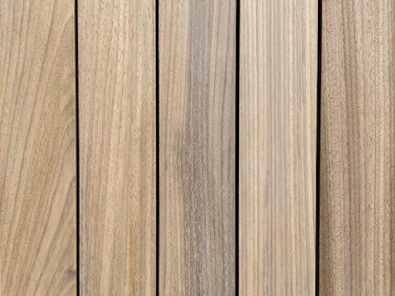 Close-up of vertical wooden planks with visible grain and narrow gaps, warm light-brown tones.