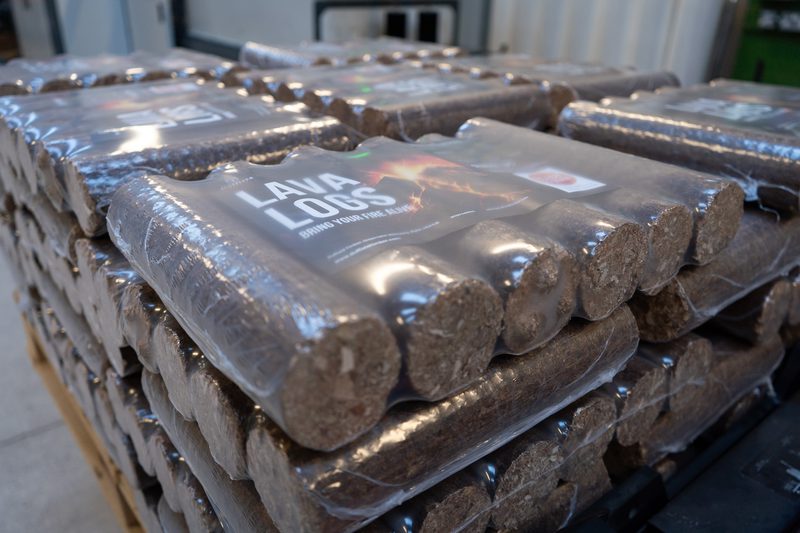 Stacks of lava logs wrapped in plastic on pallets in a warehouse, with a visible label reading "LAVA LOGS."