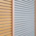 Close-up of three horizontal slatted panels in warm orange, pale gray, and dark gray, separated by vertical wooden dividers.