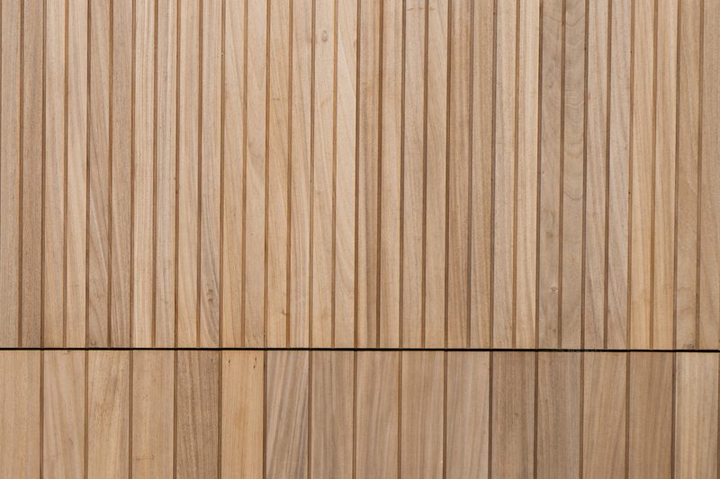 Vertical wooden planks form a wall, with a thin dark seam running horizontally across the middle, showing warm brown grain.