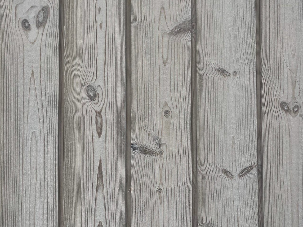 Vertical wooden planks showing grain and knots; weathered gray wood surface.