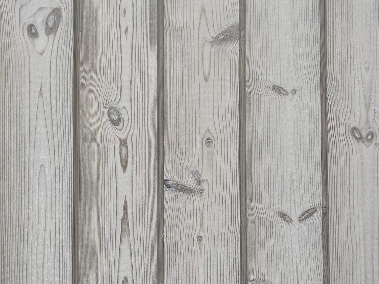 Close-up of vertical weathered wooden planks with visible grain patterns and knots.