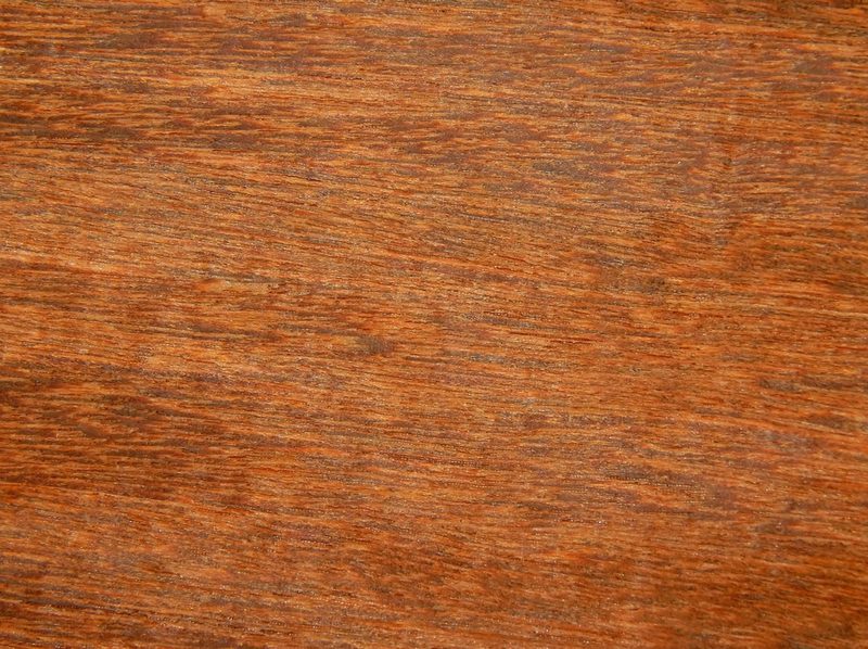 Close-up of a warm reddish-brown wood surface with prominent grain lines and natural texture.