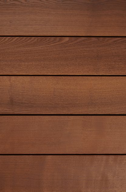 Close-up of horizontal brown wooden planks with visible grain and narrow seams, forming a warm rustic wall.