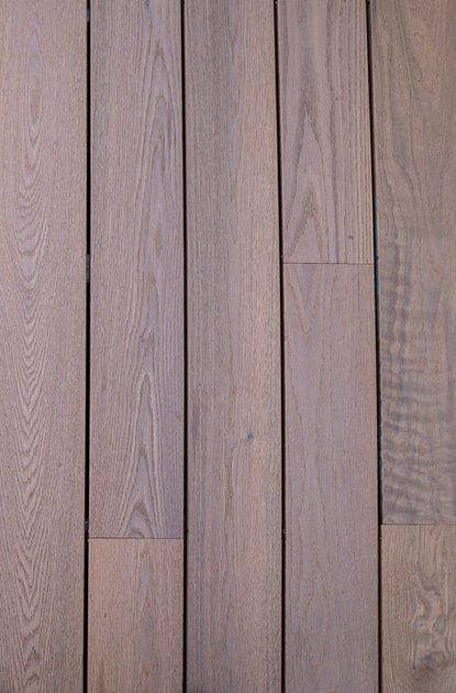 Close-up of horizontal brown wooden planks with visible grain and narrow seams, forming a warm rustic wall.
