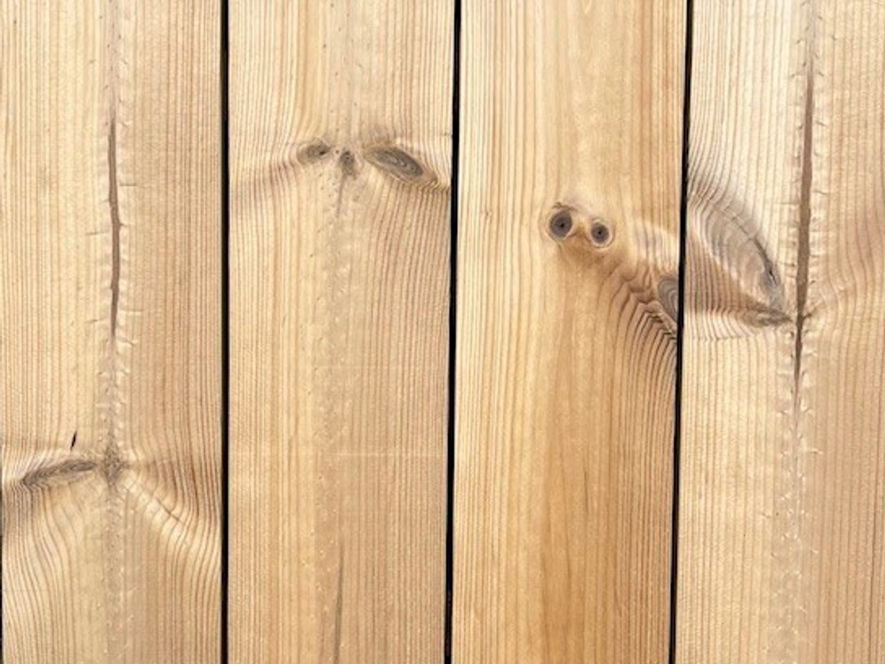 Close-up of vertical wooden planks showing natural grain, knots, and small metal screws along the edges.
