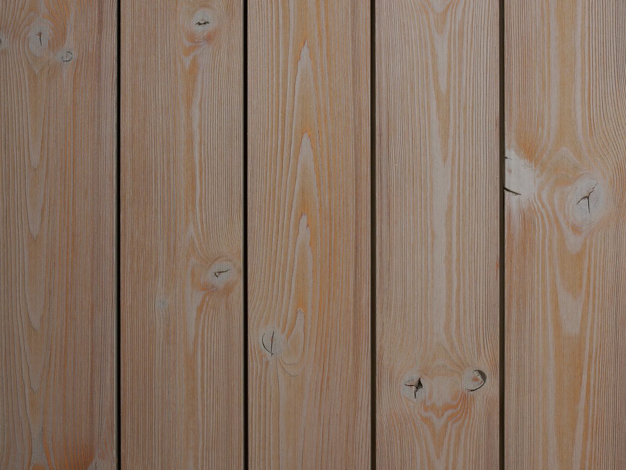 Close-up of vertical wooden planks with visible grain patterns and knots in warm brown tones.