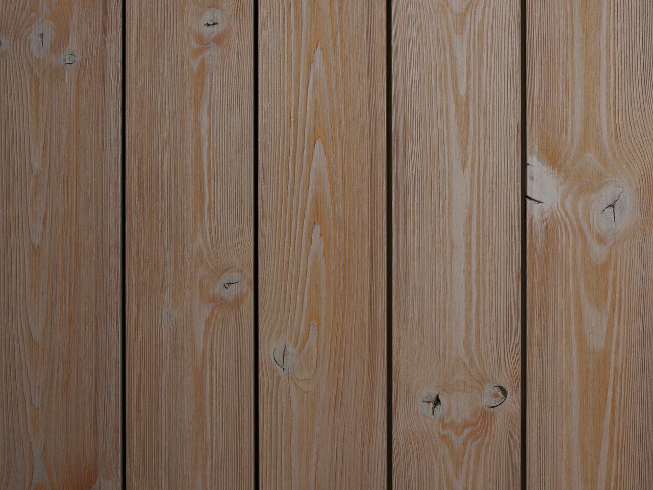 Vertical wooden planks with visible grain and knots; warm brown tones and slim gaps between boards.