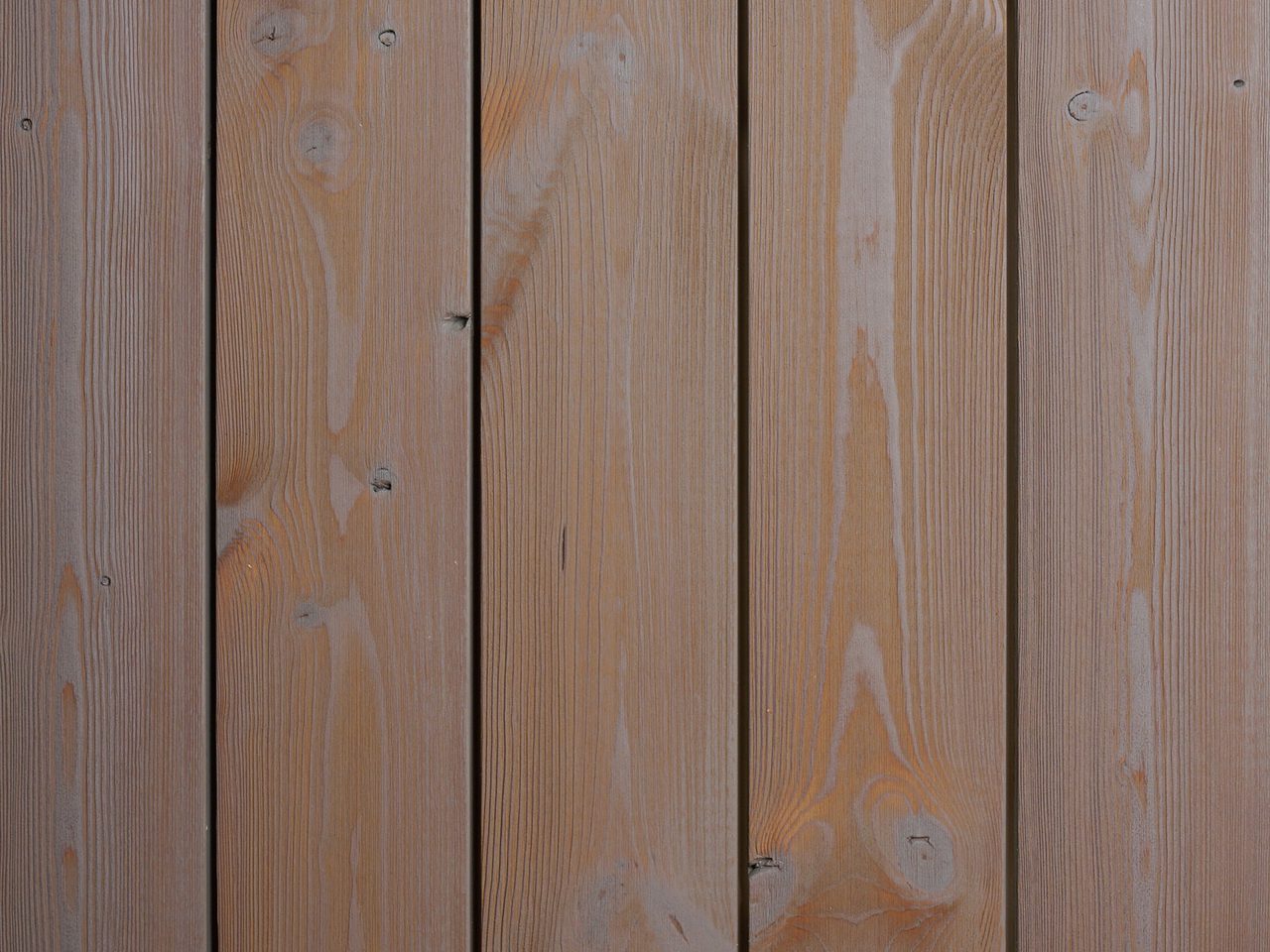 Close-up of vertical wooden deck planks with natural grain, knots, and narrow gaps.