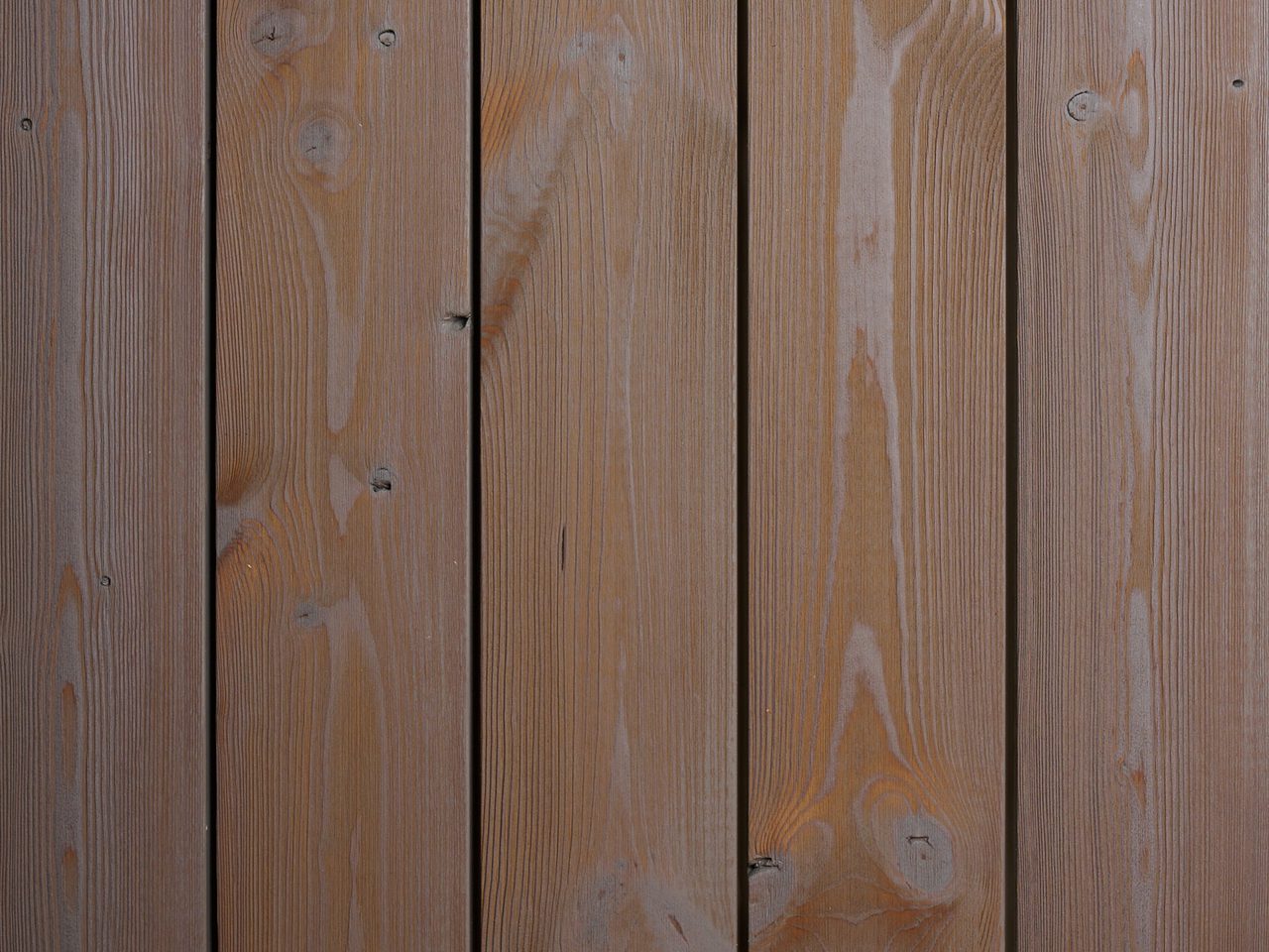 Close-up of vertical wooden deck boards showing natural grain, knots, and narrow gaps between the planks.