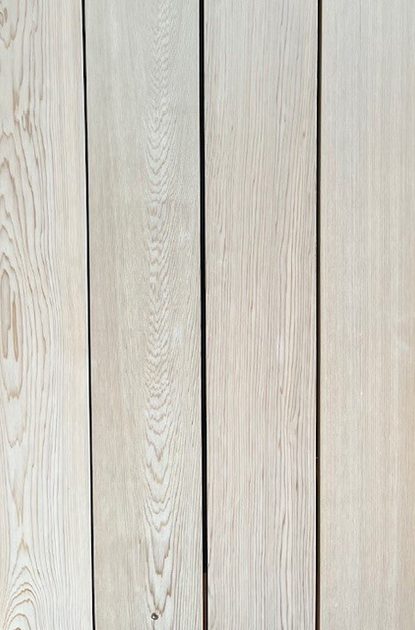 Vertical light-colored wooden planks with visible grain and dark gaps between boards.
