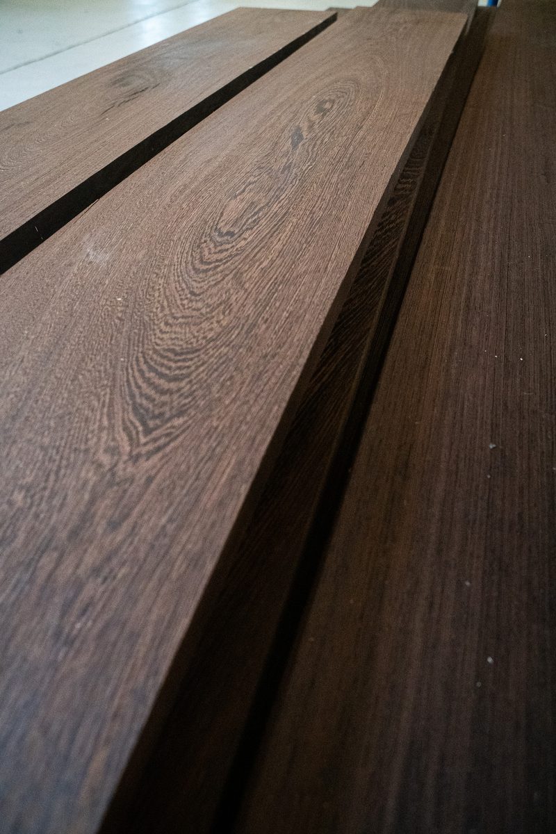Close-up of brown wooden planks with prominent grain patterns, stacked with narrow dark gaps between boards.