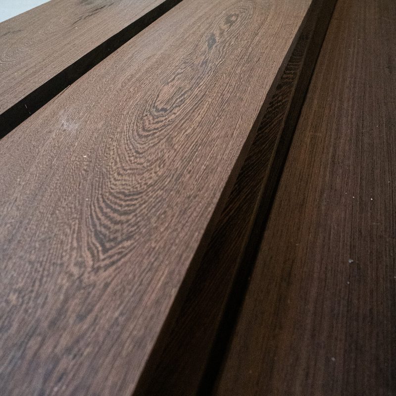 Close-up of brown wooden planks with prominent grain patterns, stacked with narrow dark gaps between boards.