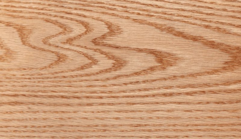 Close-up of a wooden surface with light brown tones and prominent wood grain patterns.