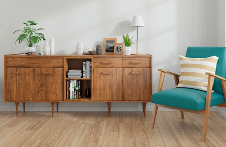 Mid-century wooden sideboard with cabinets and open shelves, decorative items and a lamp; teal chair with a striped cushion beside a tall blue vase with branches.