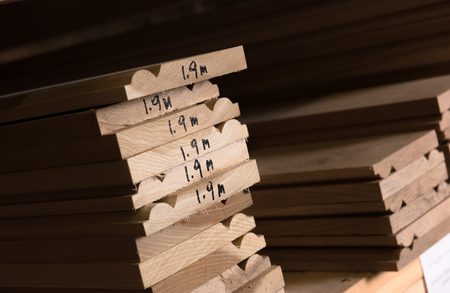 Stack of light wood boards with ends marked 1.9m; arranged in a neat pile with shadows.