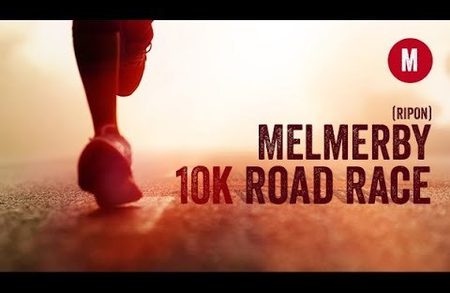 Close-up of a runner's feet on a sunlit road with warm tones; overlay reads 'Melmerby 10K Road Race' and a red circular 'M' logo.