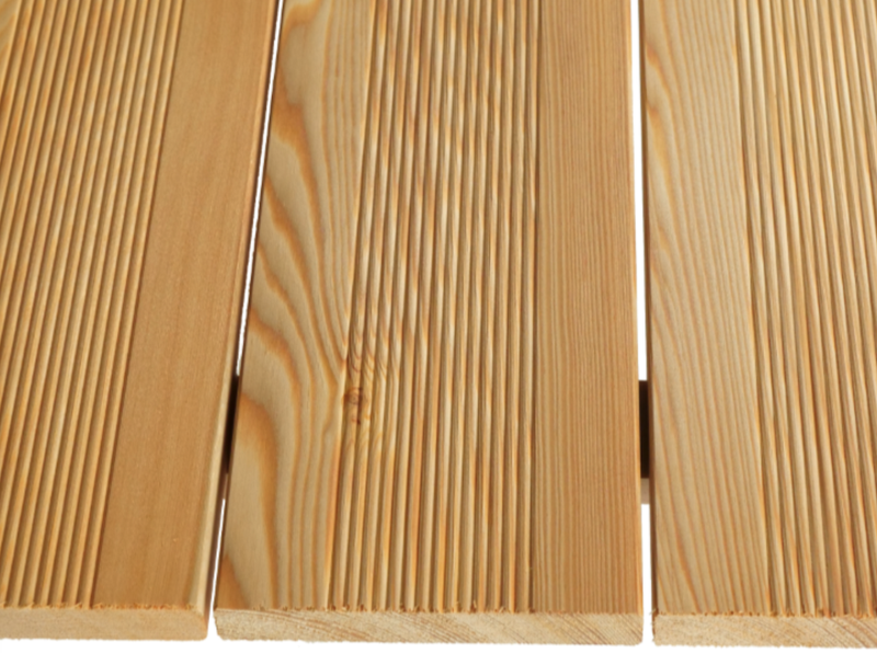 Close-up of three light-brown wooden boards with pronounced grain patterns and narrow gaps between them.