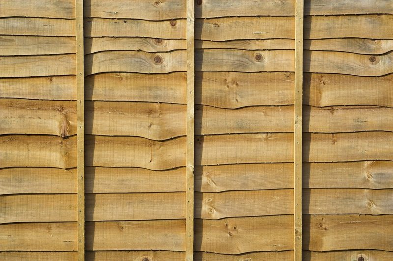 Close-up of a wooden wall with horizontal planks and vertical supports; warm brown wood grain, knots, and subtle shadows between boards.