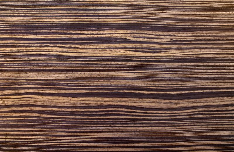 Close-up of a wooden surface with dark, wavy grain lines and warm brown tones.