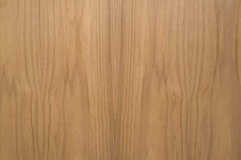 Close-up of a warm brown wood surface with distinct vertical grain patterns and subtle color variation.