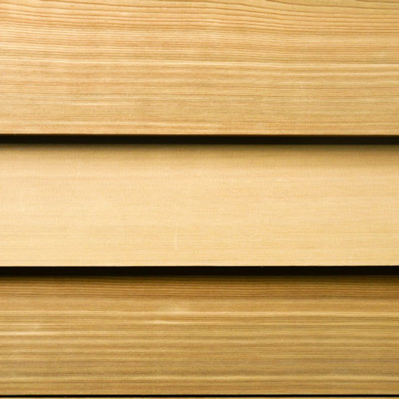 Three horizontal wooden planks with visible grain, ranging from light to medium brown, with small gaps between them.