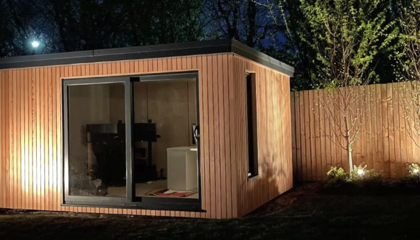 Douglas fir vertical cladding on a garden room, illuminated by lighting.
