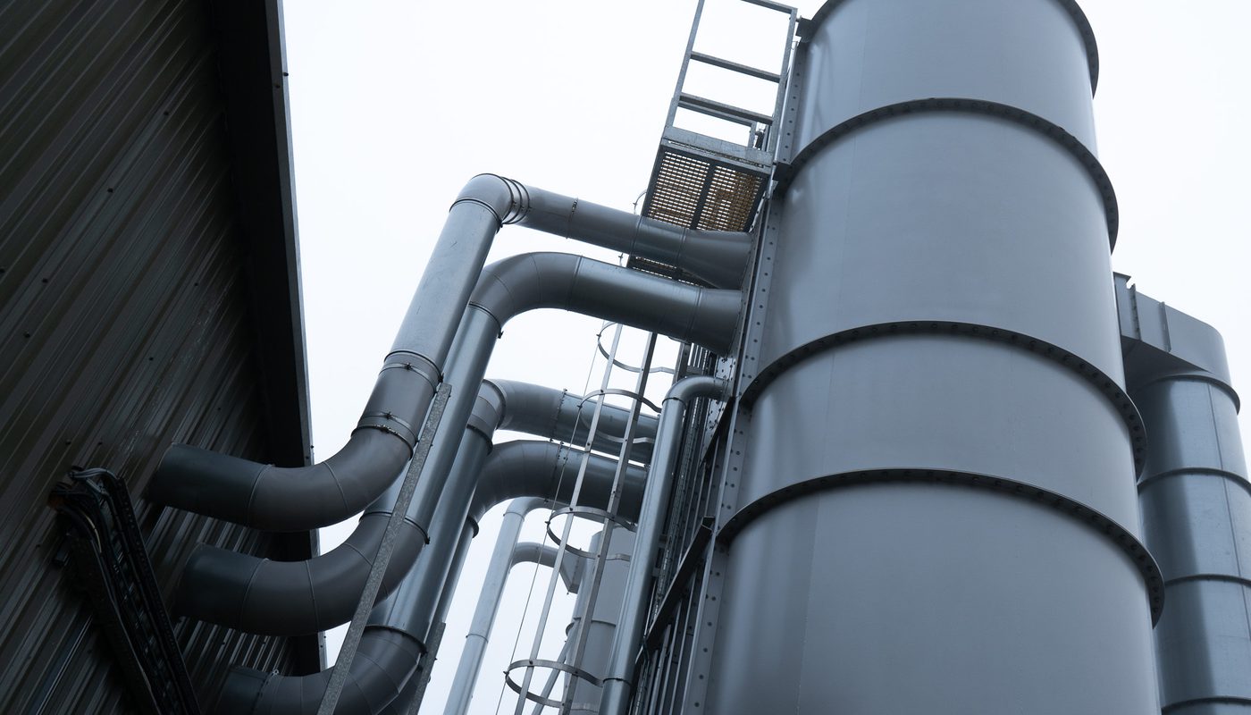 A close-up view of a large industrial hopper with metal pipes leading from it.
