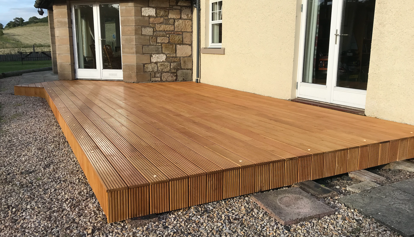 A closeup of a deck made from Iroko at a countryside property.