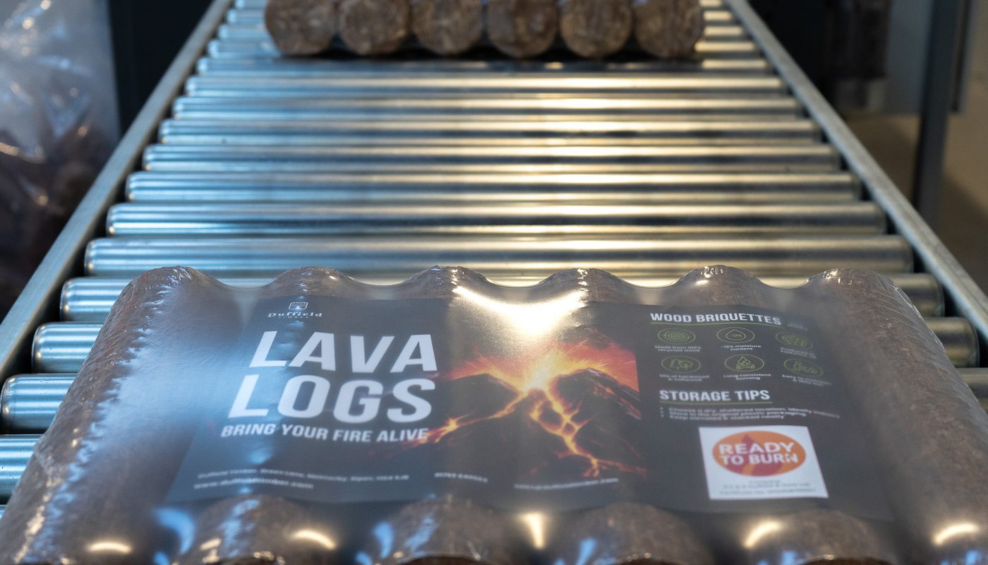 A stack of packaged Lava Log wood briquettes labeled and moving along a conveyor belt.