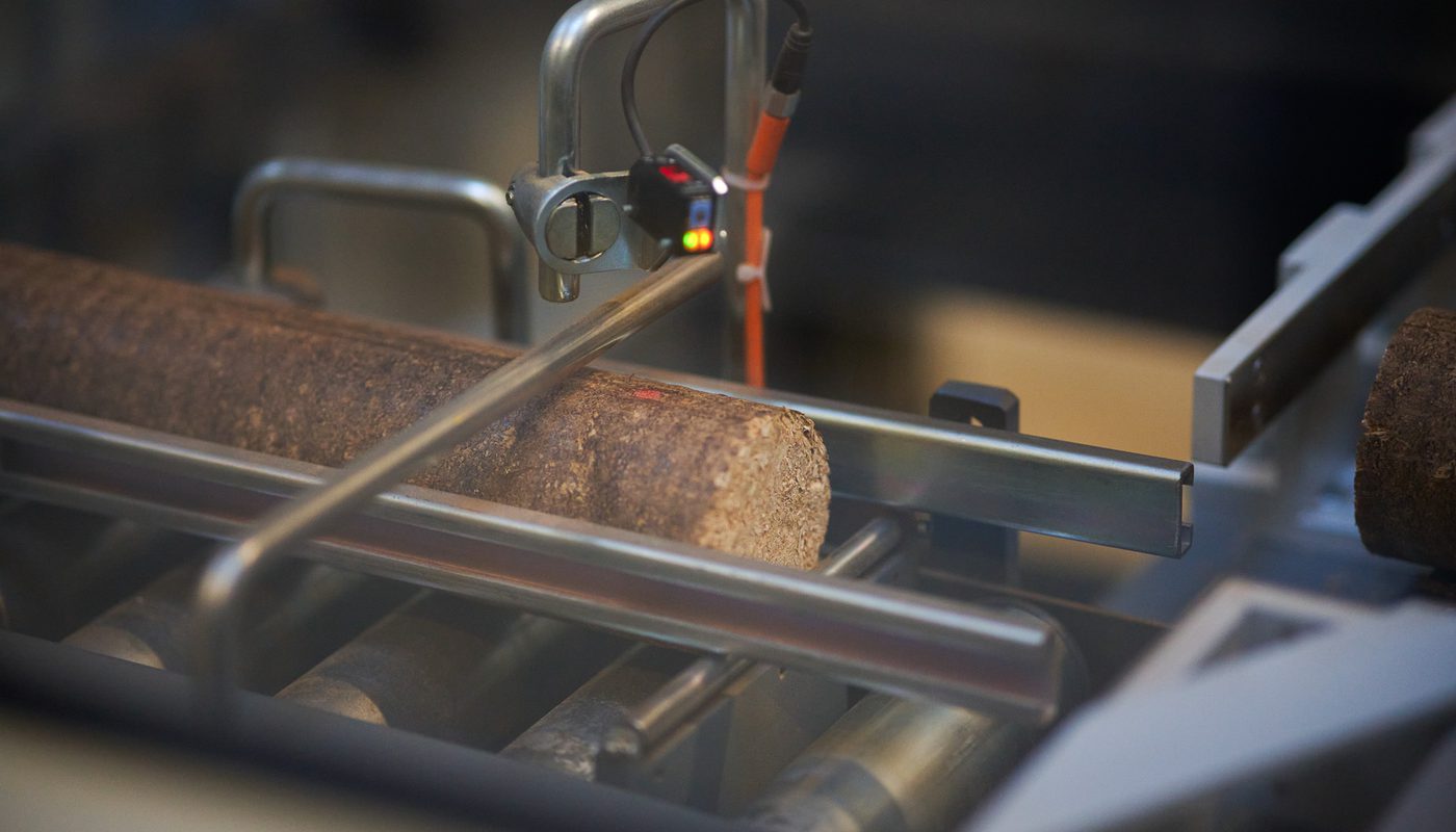 A freshly-cut Lava Log wood briquette passing through a sensor during the packaging process.
