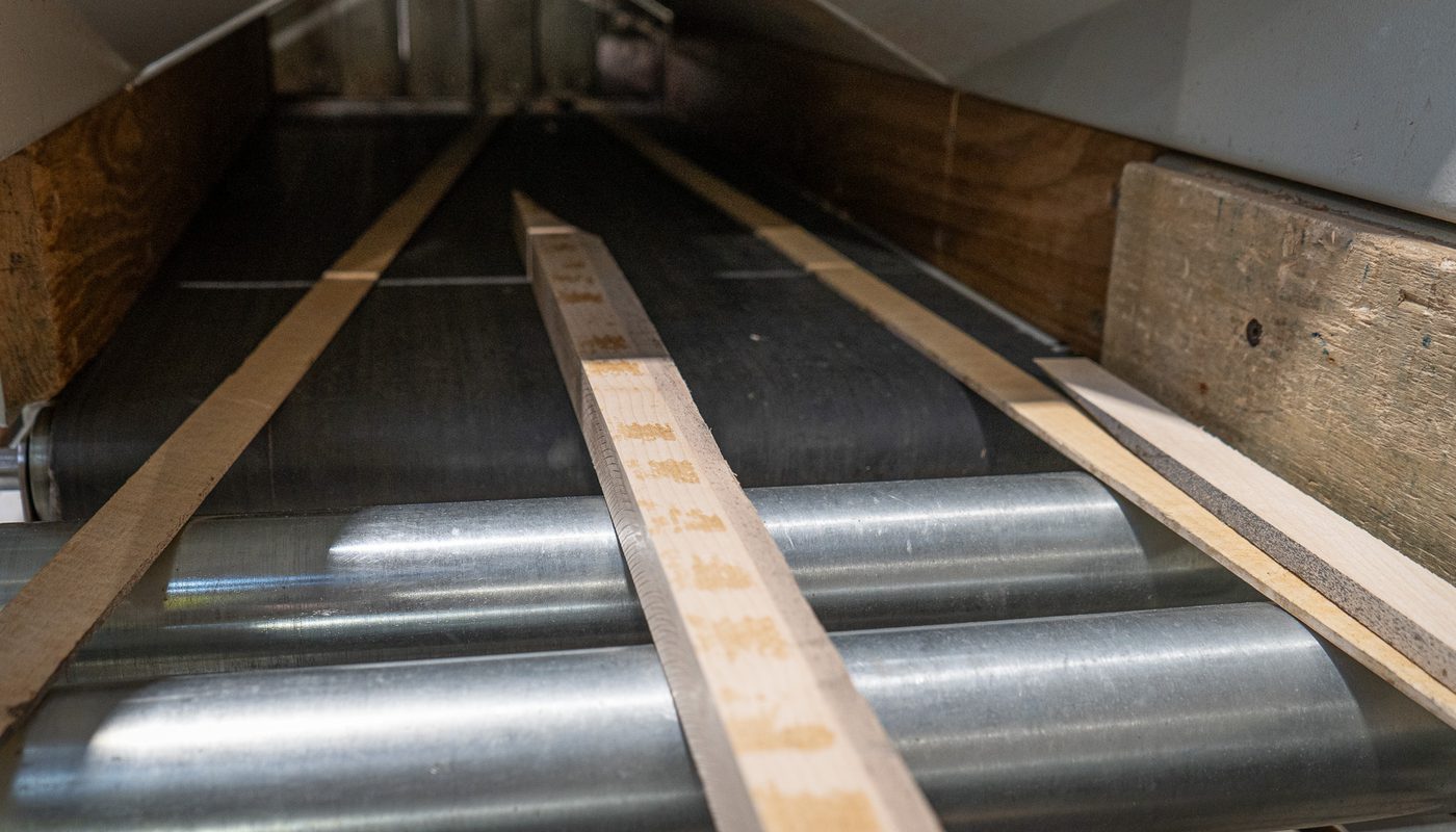 High quality timber off-cuts on a roller conveyor at Duffield Timber's factory, ready for processing into wood briquettes.
