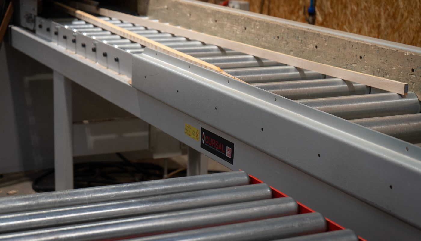 High quality timber off-cuts on a roller conveyor at Duffield Timber's factory, ready for processing into wood briquettes.