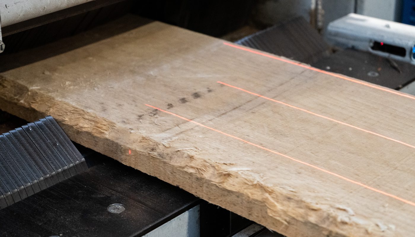 A timber board being ripped with a laser-guided cutting machine at Duffield Timber's factory.