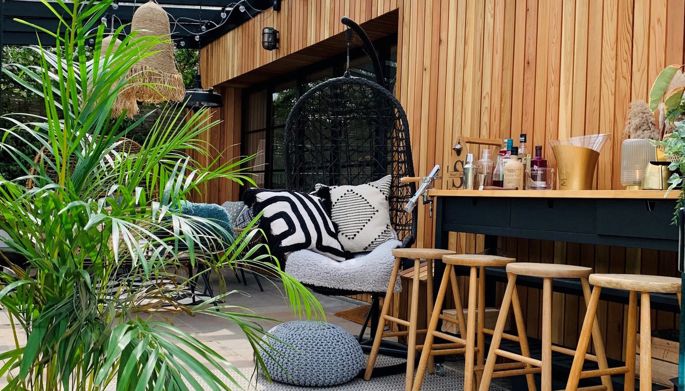 A stylish outdoor space with a garden room or summerhouse completed in vertical western red cedar cladding.