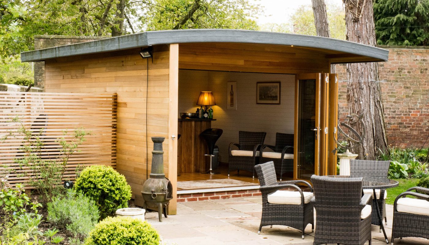 A design-led garden room clad horizontally with western red cedar, with outdoor furniture in foreground.