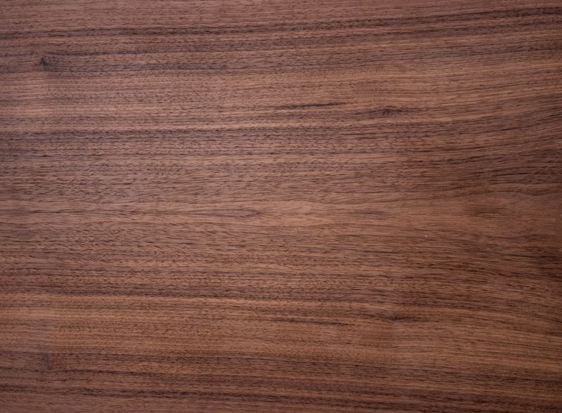Close-up of a warm brown wooden surface with pronounced horizontal grain, subtle knots, and a smooth, polished texture.