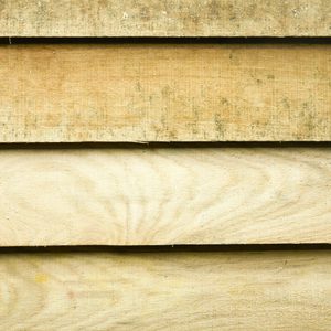 Close-up of weathered horizontal wooden planks in light beige, showing natural grain, texture, and thin seams between boards.