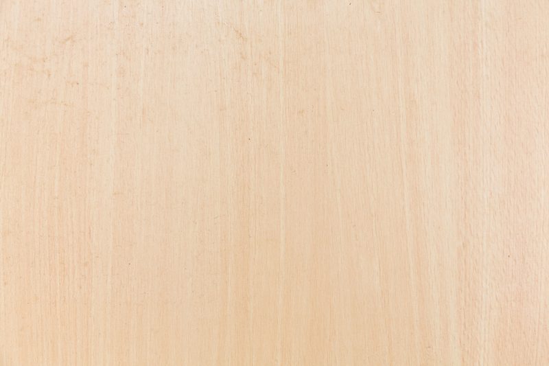 Light beige wooden surface with fine grain and subtle vertical streaks across a smooth plank.