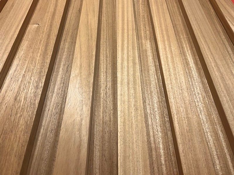 Close-up of several parallel wooden planks with varying brown tones, visible grain patterns, and a glossy finish.