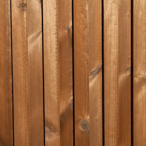 Close-up of vertical wooden planks in warm brown tones, showing grain and knots, resembling a wooden fence or panel.