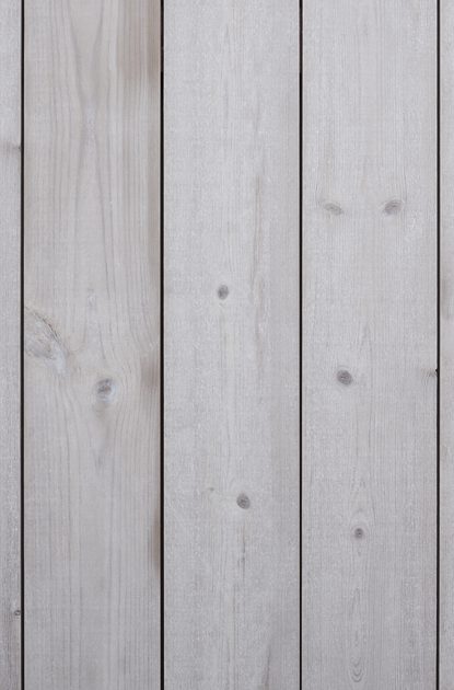 Vertical light-gray wooden planks with visible grain and knots, and narrow gaps between boards.