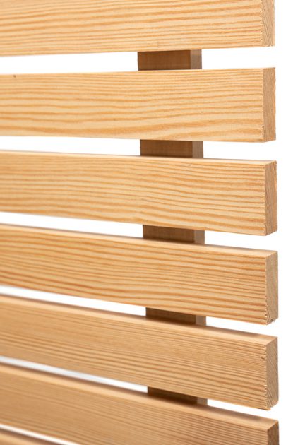 Close-up of pale wood slats with visible grain, arranged horizontally with even gaps, forming a slatted panel against a white background.