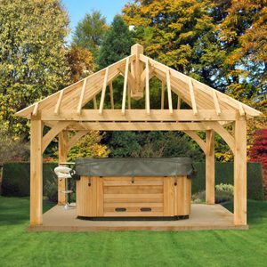 Wooden outdoor pavilion over a hot tub in a green backyard, with autumn trees in the background.
