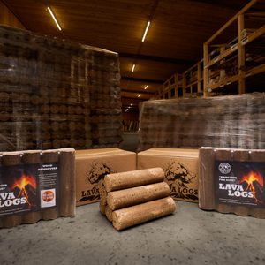 Stacks of 'Lava Logs' wood briquettes, manufactured by Duffield Timber, displayed in a timber warehouse with shelves and other wood products.