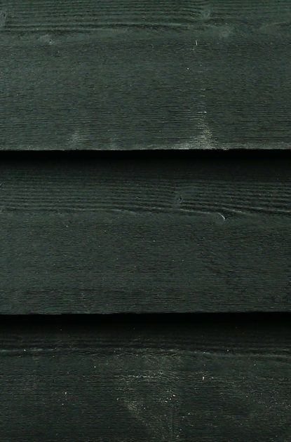 Close-up of dark, weathered wooden planks arranged horizontally, showing grain texture and narrow seams.