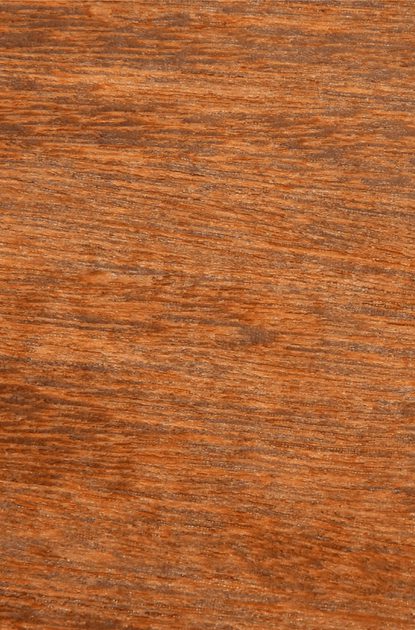 Close-up of a warm brown wood surface with visible grain patterns and subtle texture.