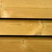 Close-up of three horizontal wooden planks with visible grain, knots, and a warm golden-brown color.